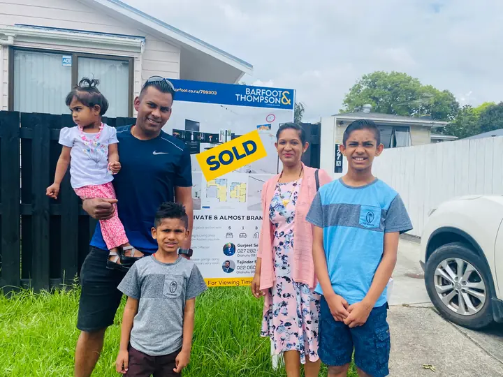 A family celebrates at the SOLD sign